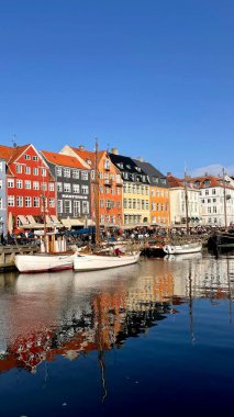 Nyhavn, Kopenhag 'ın canlı liman bölgesi. Renkli tarihi binalar kanal boyunca uzanır, kenetlenmiş tekneler de manzaralı bir cazibe katar. İnsanlar açık hava kafelerini ve hareketli atmosferi severler..