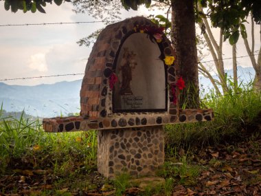 Yolun kenarındaki Bakire Heykeli. Dağ Arkaplanına Karşı Dikenli Tel.