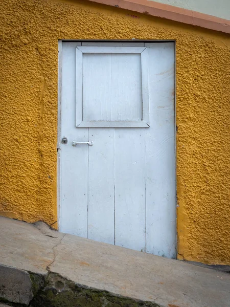 黄色の背景の白い扉 コロンビアのアンティオキアの町の坂の通り — ストック写真