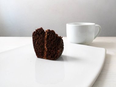 Fıstık ezmeli vejetaryen çikolatalı kek. Beyaz arka planda beyaz bir fincanın yanında çikolata kremalı.