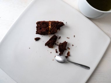 Fıstık ezmeli vejetaryen çikolatalı kek. Beyaz arka planda beyaz bir fincanın yanında çikolata kremalı.