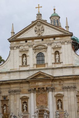 Karmaşık heykeller, süslü detaylar ve altın bir haç içeren büyük bir Barok kilise cephesi. Avrupa dini mimarisinin çarpıcı bir örneği