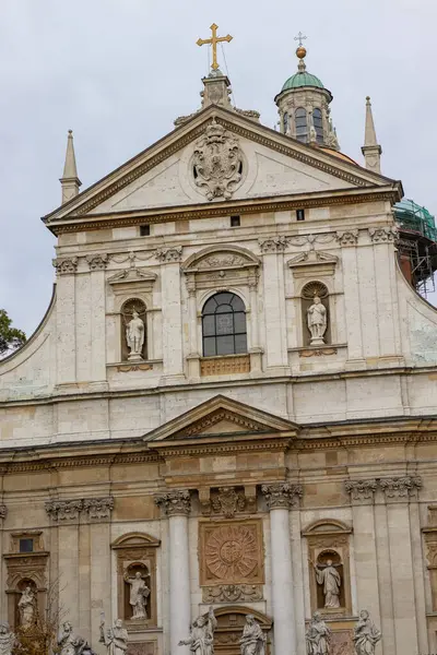 Karmaşık heykeller, süslü detaylar ve altın bir haç içeren büyük bir Barok kilise cephesi. Avrupa dini mimarisinin çarpıcı bir örneği