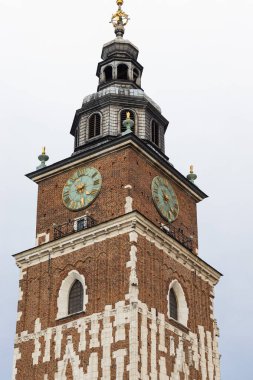 Krakow Belediye Binası Kulesi 'nin orta ölçekli görüntüsü, saat yüzleri, tuğla işçiliği ve kule. Polonya 'nın Krakow kentindeki bulutlu gökyüzüne karşı mimari detaylar