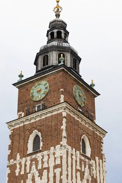 Krakow Belediye Binası Kulesi 'nin orta ölçekli görüntüsü, saat yüzleri, tuğla işçiliği ve kule. Polonya 'nın Krakow kentindeki bulutlu gökyüzüne karşı mimari detaylar