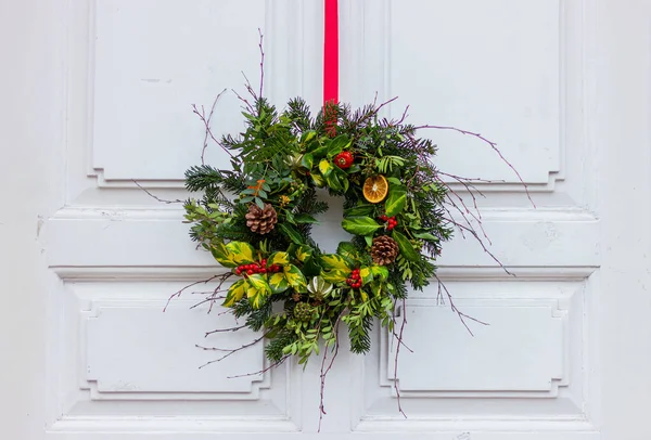 Christmas wreath on white front door close-up. winter and New Year festive street decorations