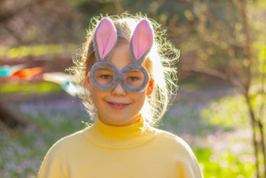 Bahçede tavşan kulağı olan gözlüklü gülen kız. Paskalya tavşanı komik kostüm.