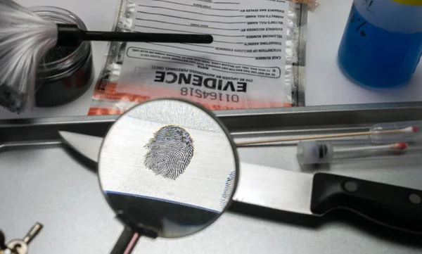 Police investigation of fingerprint on a knife, concept image