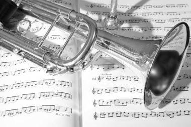 Nota kağıdının arka planında trompet çalan müzik aletinin görüntüsü