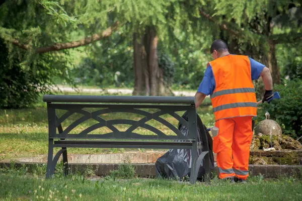 stock image sweeper cleaning the park, man with hi vis safety vest collects garbage