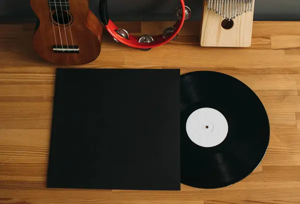 Music album mockup. Vinyl record with paper envelope with musical instruments on wooden background.