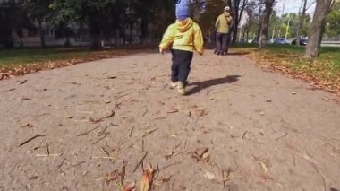 Çocukların bacakları kaldırım boyunca koşar, ve baba bebek arabasını şehir parkına iter. Sonbahar mevsiminin neşesi açık gökyüzünün altında. Kopyalama alanı - rüya kavramı, aile yürüyüşleri