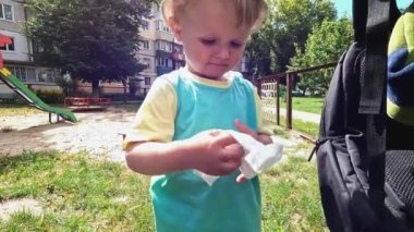 The kid wipes dirty hands with a white napkin. Smiling boy cleans germs from fingers. Proper upbringing. Copy space - concept of cleanliness, personal hygiene, baby hygiene, healthcare, habit