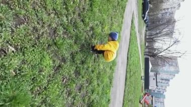 Dikey video, bir çocuk sarı bir karahindibayı inceliyor. Gelecek nesiller için doğal kaynakların korunması ve korunması. Uzayı kopyala - Çevredeki dünyayı çalışma kavramı, ekoloji