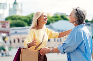Güzel, mutlu, son sınıf kadınları şehir merkezinde buluşup alışveriş yapıyorlar güzel ve neşeli yaşlı kadın yetişkin insanlar kaynaşıyor ve dışarıda eğleniyorlar.