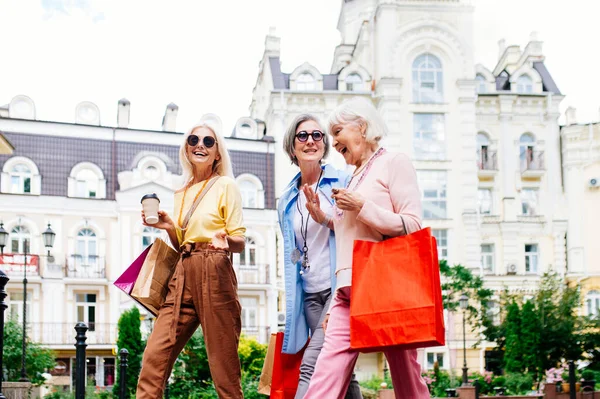 市内中心部で屋外とショッピングを満たす美しい幸せなシニア女性 かなりと喜び古い女性の大人の人々が結合し 屋外で楽しみを持っています — ストック写真