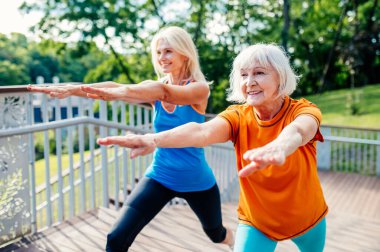 Dışarıda antrenman yapan bir grup güzel ve sportif son sınıf öğrencisi yetişkin arkadaşlar sağlıklı ve formda kalmak için parkta spor yapıyorlar.