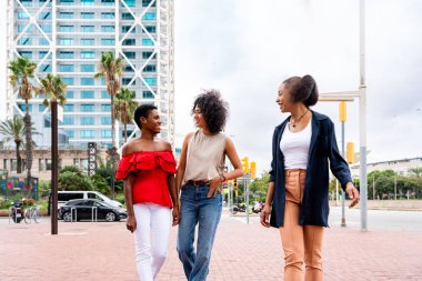 Mutlu güzel İspanyol asıllı Güney Amerikalı ve siyah kadınlar dışarıda buluşup eğleniyorlar siyah yetişkin kadın arkadaşlar birlikte vakit geçiriyorlar ve alışveriş için şehirde dolaşıyorlar.