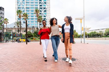 Mutlu güzel İspanyol asıllı Güney Amerikalı ve siyah kadınlar dışarıda buluşup eğleniyorlar siyah yetişkin kadın arkadaşlar birlikte vakit geçiriyorlar ve alışveriş için şehirde dolaşıyorlar.