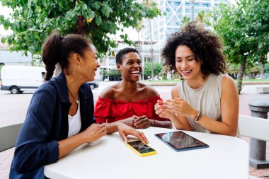 Mutlu güzel İspanyol asıllı Güney Amerikalı ve siyahi kadınlar dışarıda buluşup eğleniyorlar siyahi yetişkin kadın arkadaşlar bir barda birlikte vakit geçiriyorlar.