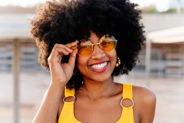 Beautiful young happy african woman with afro curly hairstyle strolling in the city - Cheerful black student portrait outdoors