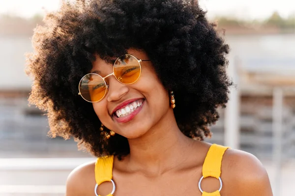 Beautiful young happy african woman with afro curly hairstyle strolling in the city - Cheerful black student portrait outdoors