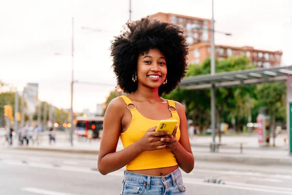 Beautiful young happy african woman with afro curly hairstyle strolling in the city - Cheerful black student girl walking on the street