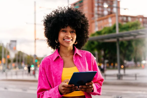 Beautiful young happy african woman with afro curly hairstyle strolling in the city - Cheerful black student girl walking on the street in the evening