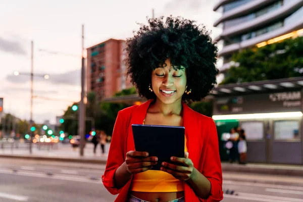 Beautiful young happy african woman with afro curly hairstyle strolling in the city - Cheerful black student girl walking on the street in the evening