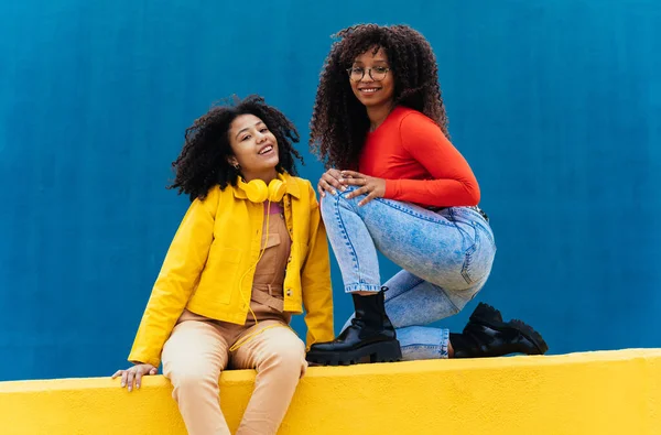 若い幸せな女性の色の青と黄色の壁にポーズ 十代の女の子一緒に学校の後に時間を過ごす — ストック写真
