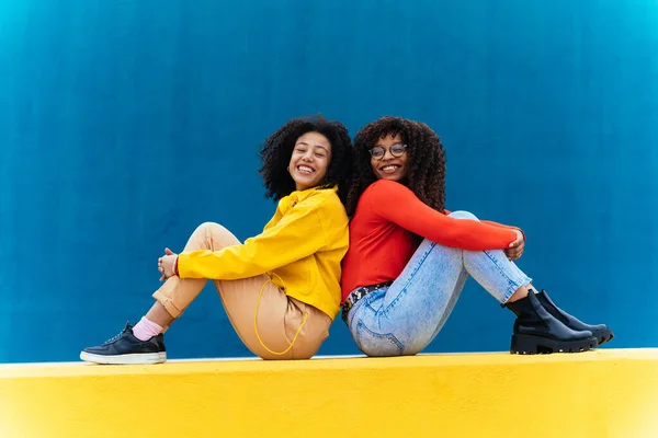 若い幸せな女性の色の青と黄色の壁にポーズ 十代の女の子一緒に学校の後に時間を過ごす — ストック写真