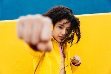 Genç ve mutlu bir kadın dans ediyor ve dışarıda eğleniyor. Genç, sarı ve mavi kentsel alanda akıllı telefon ve kulaklıkla müzik dinliyor.