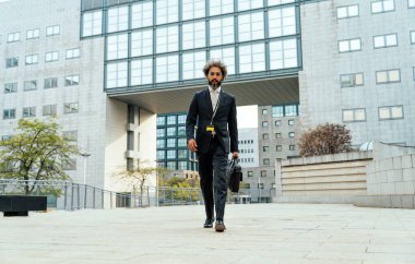 Başarılı bir iş gününün ardından ofisinin önünde yürüyen genç girişimci bir işadamı.