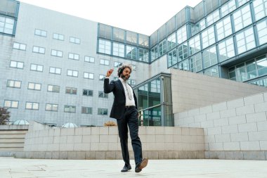 Genç girişimci iş adamı ofis dışında müzik dinleyip dans ediyor. İş hayatında özgürlük ve başarı kavramı