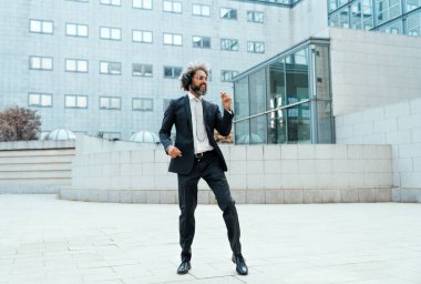Genç girişimci iş adamı ofis dışında müzik dinleyip dans ediyor. İş hayatında özgürlük ve başarı kavramı