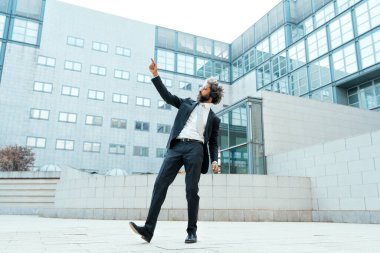Genç girişimci iş adamı ofis dışında müzik dinleyip dans ediyor. İş hayatında özgürlük ve başarı kavramı