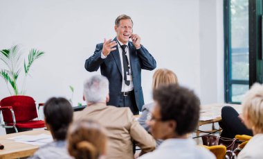 Bir konferans toplantısının sinematik görüntüsü. İş adamları bir odada oturup motivasyon koçunu dinliyor. Bir Öz Gelişim ve Gelişim Özel Olayının Temsili