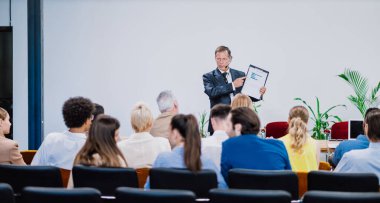 Bir konferans toplantısının sinematik görüntüsü. İş adamları bir odada oturup motivasyon koçunu dinliyor. Bir Öz Gelişim ve Gelişim Özel Olayının Temsili