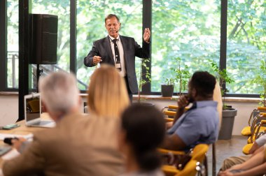 Bir konferans toplantısının sinematik görüntüsü. İş adamları bir odada oturup motivasyon koçunu dinliyor. Bir Öz Gelişim ve Gelişim Özel Olayının Temsili