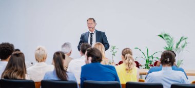 Bir konferans toplantısının sinematik görüntüsü. İş adamları bir odada oturup motivasyon koçunu dinliyor. Bir Öz Gelişim ve Gelişim Özel Olayının Temsili