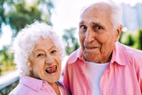 昔ながらのモダンなカップルはファッショナブルな色の服 若い祖母と祖父は屋外で楽しく野生になっています 中で若い感じの高齢者の表現 — ストック写真