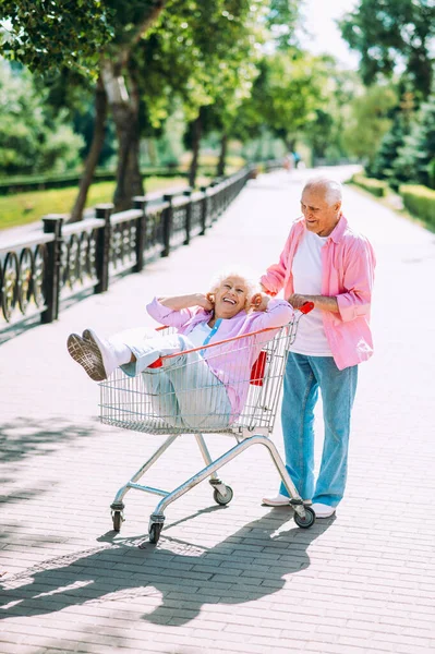 Old modern couple dressing fashionable colored clothes. Youthful grandmother and grandfather having fun outdoor and going wild. Representation of elderly people feeling young inside