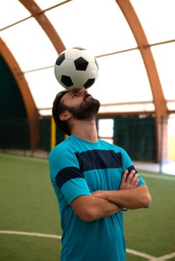 Futbol serbest stil oyuncusunun suni çim kortunda top oynarken çekilmiş sinematik bir görüntüsü. Spor ve insan yaşam tarzı kavramı