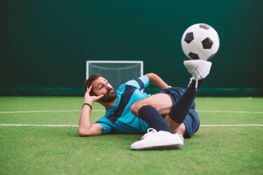 Futbol serbest stil oyuncusunun suni çim kortunda top oynarken çekilmiş sinematik bir görüntüsü. Spor ve insan yaşam tarzı kavramı