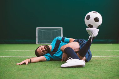 Futbol serbest stil oyuncusunun suni çim kortunda top oynarken çekilmiş sinematik bir görüntüsü. Spor ve insan yaşam tarzı kavramı