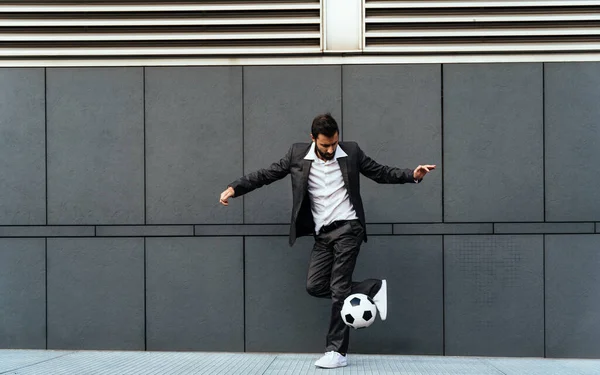 Image of a businessman and soccer freestyle player making tricks with the ball on the street. Concept about sport and business people