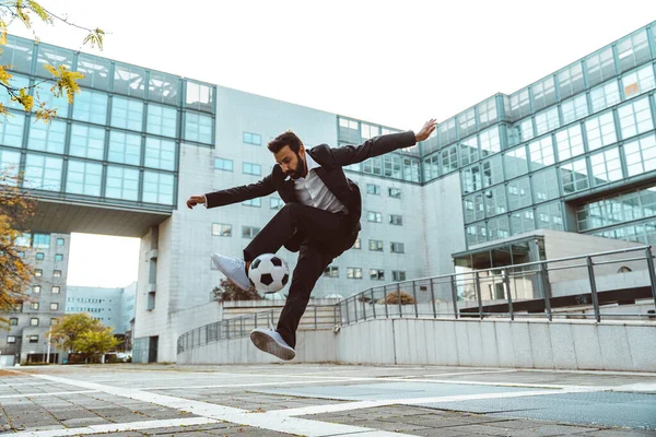 Image of a businessman and soccer freestyle player making tricks with the ball on the street. Concept about sport and business people