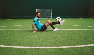 Futbol serbest stil oyuncusunun suni çim kortunda top oynarken çekilmiş sinematik bir görüntüsü. Spor ve insan yaşam tarzı kavramı