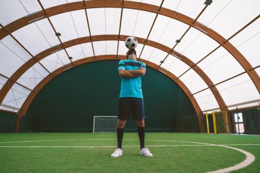 Futbol serbest stil oyuncusunun suni çim kortunda top oynarken çekilmiş sinematik bir görüntüsü. Spor ve insan yaşam tarzı kavramı