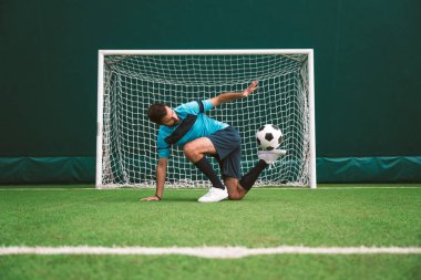 Futbol serbest stil oyuncusunun suni çim kortunda top oynarken çekilmiş sinematik bir görüntüsü. Spor ve insan yaşam tarzı kavramı